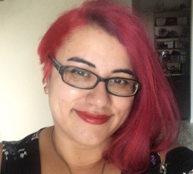 An image of me from 2019. Pink hair, blue glasses.